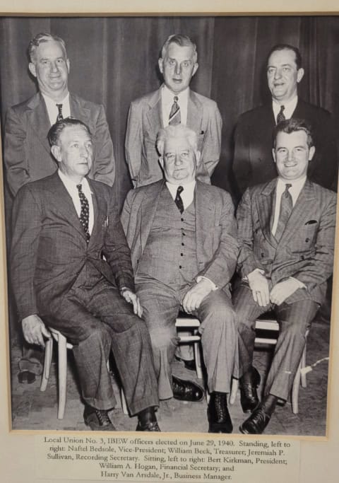 Group photo of JIBE officers from 1940, seated and standing, in formal suits.