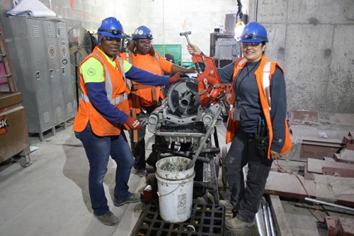 Electrical workers operating machinery at a training facility.