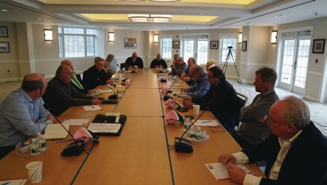 Industry leaders in a formal meeting discussing electrical industry history.