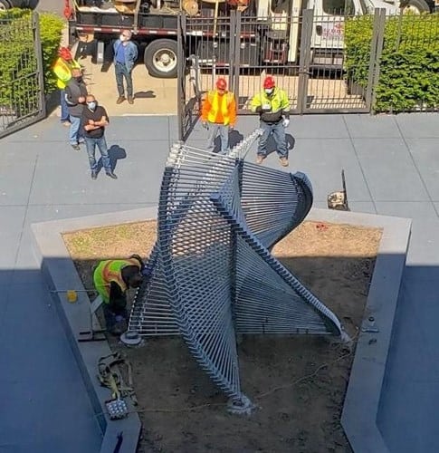Workers installing a modern spiral staircase at a construction site.
